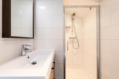 uma casa de banho branca com um lavatório e um chuveiro em Centrum-Appartementen Langstraat 5 em Zoutelande