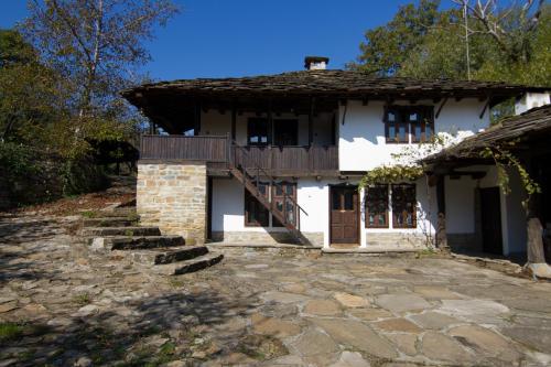 a white house with a porch and a balcony at Dedovite Kashti in Stefanovo