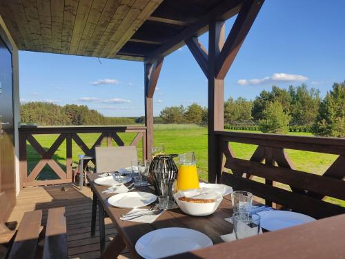 a wooden table with food on a deck with a view of a field at Wdzydzka Chatka in Wdzydze Tucholskie