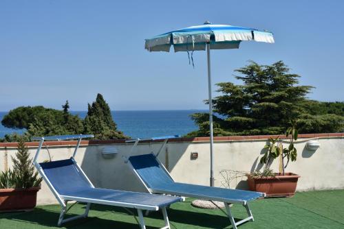 zwei blaue Stühle und ein Regenschirm auf einer Terrasse in der Unterkunft Hotel Diano Marina Mhotelsgroup in Diano Marina