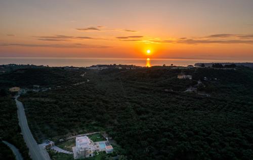 an aerial view of the sun setting over the ocean at Valentino Luxury Villa in Plános
