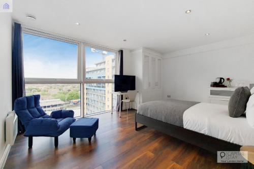 a bedroom with a bed and a chair and a large window at London ExCeL Stays in London
