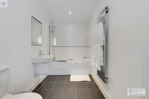 a bathroom with a sink and a tub and a toilet at London ExCeL Stays in London
