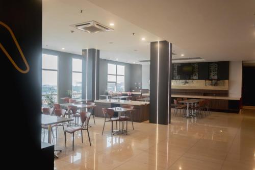 una sala da pranzo con tavoli, sedie e finestre di Rooms Inc BTC Bandung a Bandung