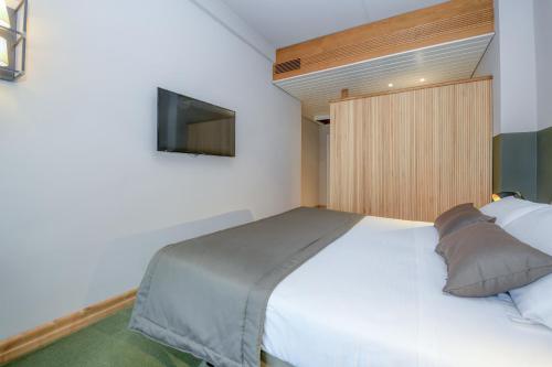 a bedroom with a bed with a tv on the wall at Hotel City in Desenzano del Garda