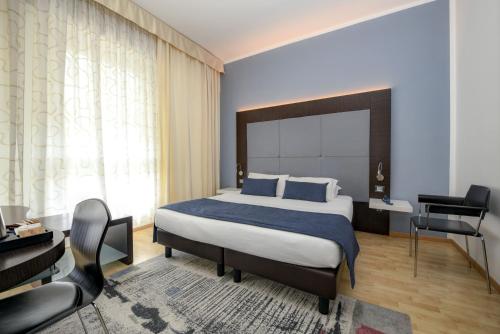 una camera con letto, scrivania e sedia di Hotel City a Desenzano del Garda
