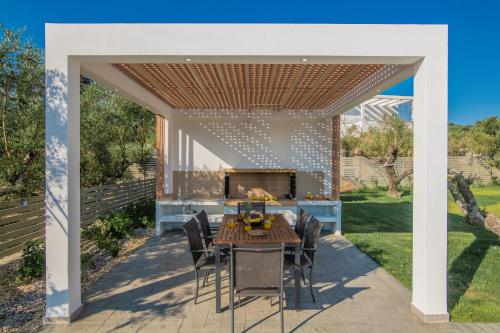 a patio with a table and chairs under a pergola at Valentino Luxury Villa in Plános