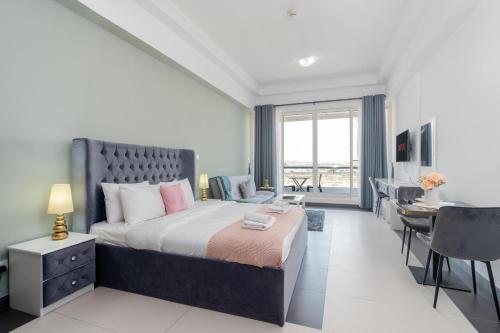 a bedroom with a large bed and a desk and a table at Vacay Lettings - Silicon Oasis Budget Friendly Studio in Dubai