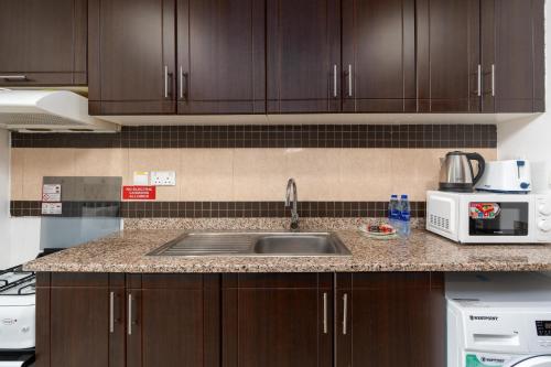 a kitchen counter with a sink and a microwave at Vacay Lettings - Silicon Oasis Budget Friendly Studio in Dubai