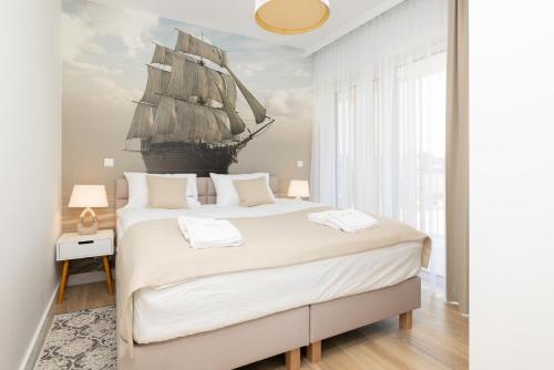 a bedroom with a large bed with a tall ship on the wall at Apartament przy Plaży z aneksem kuchennym A 24 w Świnoujściu in Świnoujście