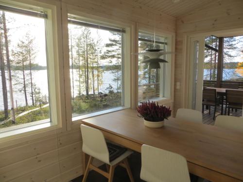 a dining room with a table and chairs and windows at Ankkuri Raijan Aitta in Mikkeli
