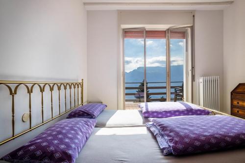 um quarto com 2 camas com almofadas roxas e uma janela em Wohnung mit grandiosem Ausblick em Tremosine Sul Garda