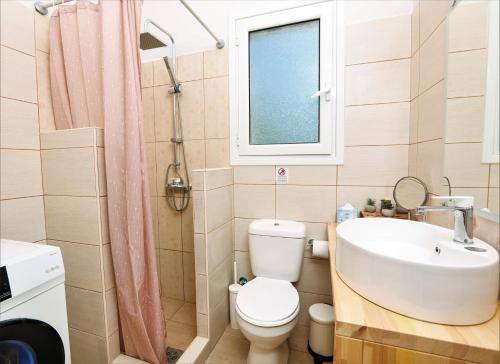 a bathroom with a toilet and a sink and a window at Terranova beach apartments - Jasmine in Ýpsos