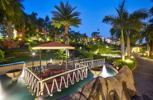 a bridge over the water in a resort at night at The Corinthians Resort & Club in Pune