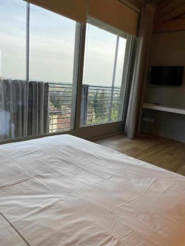 a bedroom with a white bed and large windows at Cascina Pianetta Quinta in Missaglia