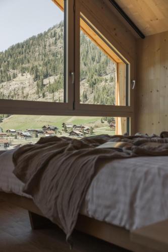 a bed in a room with a large window at Chalets Santner in Sankt Jakob in Defereggen