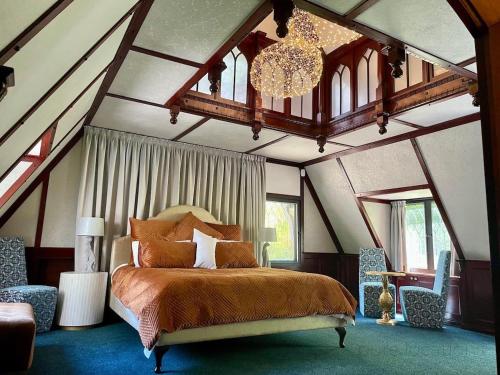 a bedroom with a large bed and a chandelier at Fernhill Estate “ Gingerbread House” in Kallista