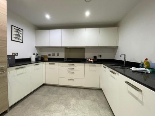 a kitchen with white cabinets and black counter tops at Luxury 2-bedroom apartment near beach in St Andrews in St. Andrews