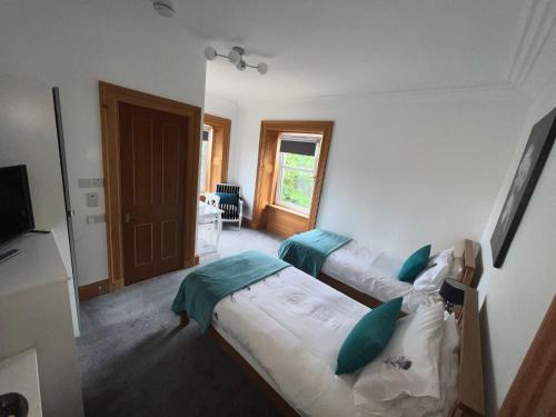 a bedroom with two twin beds and a television at Morven Guest House Carnoustie in Carnoustie