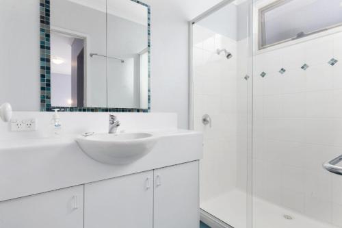 a white bathroom with a sink and a shower at Beach Bush and Birds in Lorne