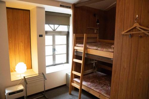 雲仙市にあるTSUDOI guest houseの二段ベッド2台と窓が備わる客室です。