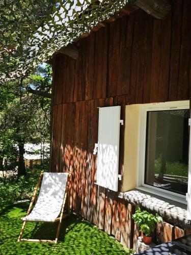 une chaise assise à côté d'un bâtiment avec fenêtre dans l'établissement Un chalet au Ventoux - Mont Serein, à Mont Serein