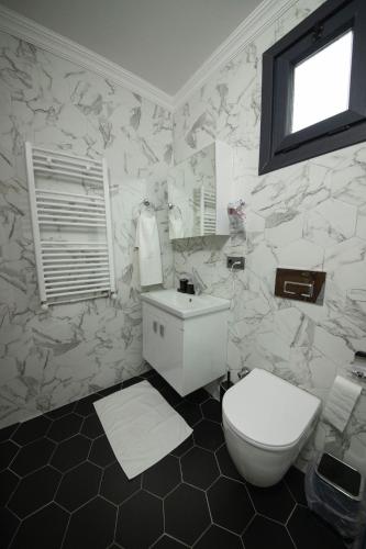 a white bathroom with a toilet and a sink at Meselik Park Bungalov in Sapanca