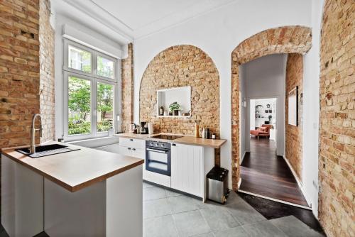 a kitchen with white cabinets and a brick wall at Trendy 3 room apartment in Kreuzberg in Berlin