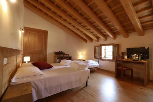 a bedroom with two beds and a television in it at Asolo Norah's Hill Agri Rooms in Caenere