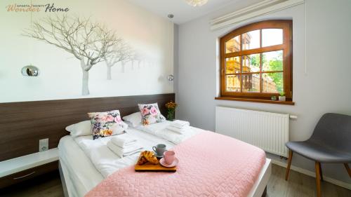 een slaapkamer met een roze bed en een dienblad bij Wonder Home - Apartamenty w cichej okolicy, niedaleko centrum Karpacza - blisko stoku i restauracji in Karpacz
