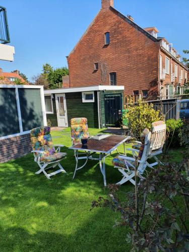 a patio with chairs and a table on the grass at Cozy Garden House kijkduin Beach in The Hague