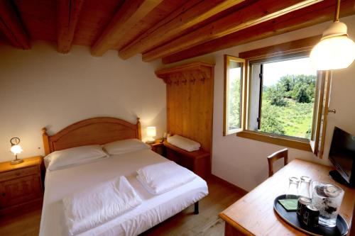 a bedroom with a white bed and a window at Asolo Norah's Hill Agri Rooms in Caenere