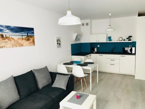 a living room with a couch and a table and a kitchen at Bliżej Morza Apartament 57 in Kołobrzeg