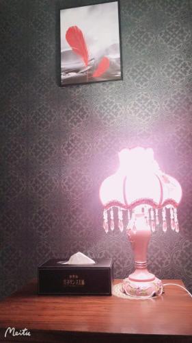 a lamp on a table next to a clock and a picture at ホテルルネサンス土浦 in Tsuchiura