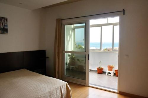 1 dormitorio con puerta corredera de cristal que da a un balcón en Apartamento moderno com vista para o mar en Sal Rei