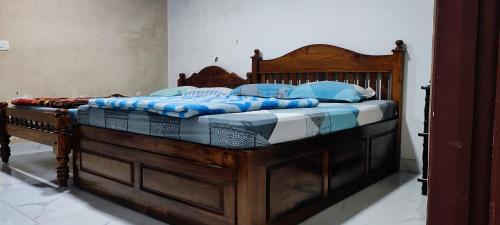 a large wooden bed with blue pillows on it at Munnar happy holidayss in Munnar