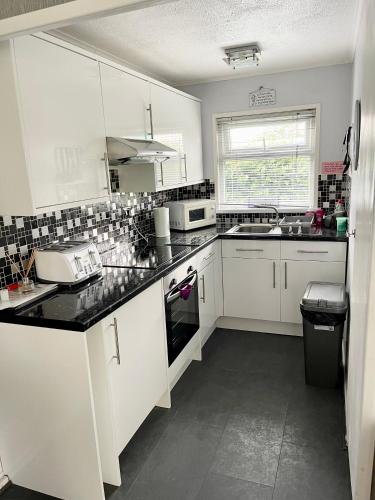 a kitchen with white cabinets and a black counter top at Sundowner Chalet Great For Families in Great Yarmouth