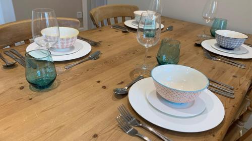 a wooden table with plates and bowls and wine glasses at Oulton Park Lodge in Little Budworth