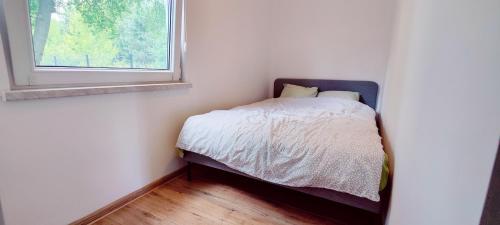 une petite chambre avec un lit et une fenêtre dans l'établissement Uroczysko Warta, à Uniejów