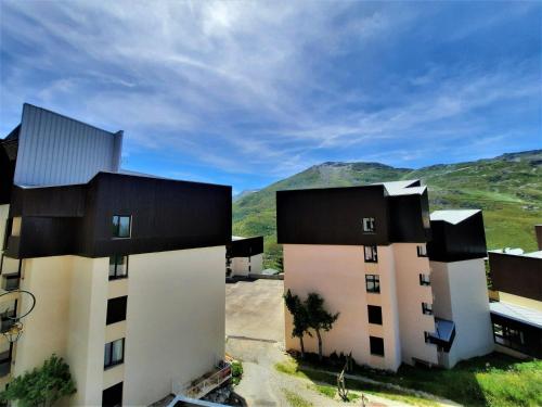 deux bâtiments avec des toits noirs et des montagnes en arrière-plan dans l'établissement Studio 3 personnes avec balcon aux Menuires, ski aux pieds - FR-1-452-50, aux Menuires