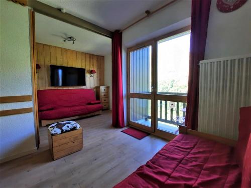 レ・メニュアールにあるAppartement Les Menuires, 2 pièces, 4 personnes - FR-1-452-165の赤いベッドと大きな窓が備わる客室です。
