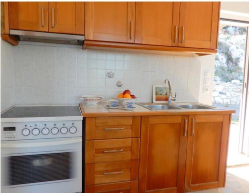 a kitchen with wooden cabinets and a stove and a sink at Athena s House in Platia Ammos