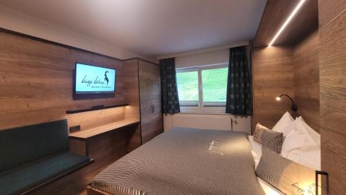 a bedroom with a bed and a tv on a wall at Haus Garni Luggi Leitner in Mittelberg