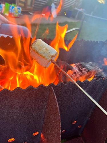 a hot dog on a stick in a grill with flames at King Richard's Luxury Lodge - Sleeps up to 8, Dog Friendly, Near Sherwood Forest at Fairview Farm in Nottingham set in 88 acres and great for Groups, Family Gatherings & Corporate events in Nottingham