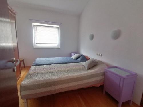 a small bedroom with a bed and a window at Apartman Perci Vrh in Tar