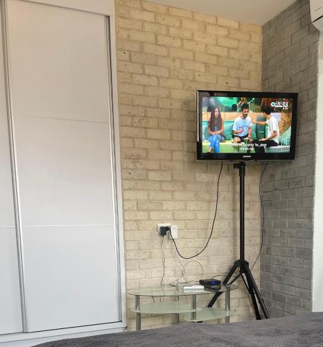a flat screen tv hanging on a brick wall at SEA& SUN in H̱adera