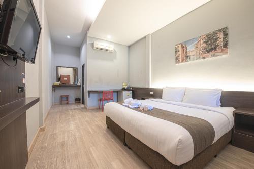 a hotel room with a large bed and a flat screen tv at Tarnsiri Boutique Resort in Kanchanaburi City