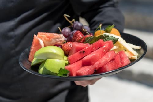 a person holding a plate of fruits and vegetables at Arocaria Mykonos in Mýkonos City