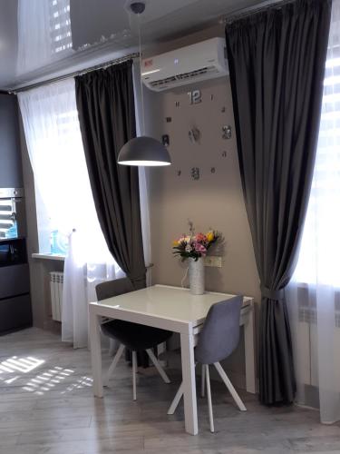 een witte tafel en stoelen in een keuken met gordijnen bij Романтичні апартаменти на центральному проспекті, великий Smart TV,преміум-підписки, кавомашина, відкритий балкон in Krivoy Rog