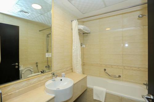 a bathroom with a sink and a tub and a toilet at Ivory Grand Hotel Apartments in Dubai